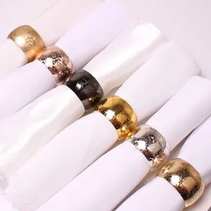 Detailed view of metal napkin rings featuring embossed floral texture in multiple colors