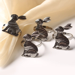 Detailed close-up of rabbit napkin rings in vintage silver on a warm table setting