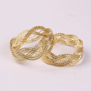 Detail of gold braided metal napkin rings with intricate hollow twisted texture