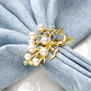 Anello portatovagliolo a forma di alce dorato con perle e cristalli su tovagliolo blu
