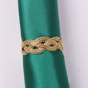 Close-up of golden woven braided napkin ring with intricate openwork mesh detail