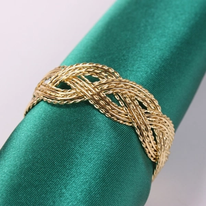 Detailed close-up of a golden woven napkin ring with intricate braided metal texture