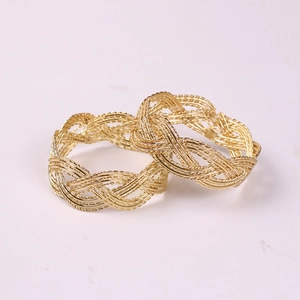 Detailed close-up of golden braided metal napkin rings with intricate weave texture