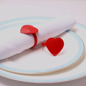 Red heart napkin rings set of two with glossy finish on a white fabric napkin and plate