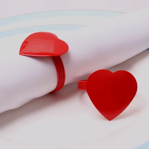 Close-up of red heart napkin ring on white cloth with elegant metal wire band detail