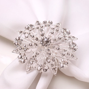 Macro view of silver floral napkin ring with sparkling crystals on white fabric