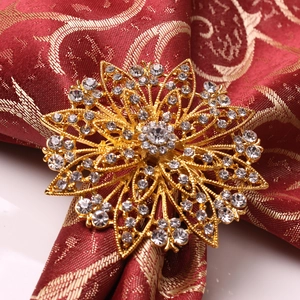 Close-up of golden floral napkin ring with sparkling rhinestones on red fabric