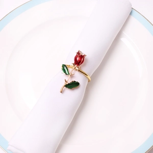 Elegant red rose napkin ring with green leaves on gold metal base and white napkin