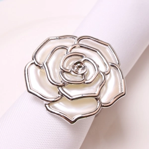 Elegant silver rose napkin ring with white enamel petals on a white linen table napkin