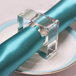Macro shot of square clear crystal napkin ring on blue satin napkin and gold-rimmed plate