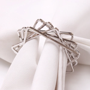 Modern geometric silver star napkin ring with polished metal triangles on white cloth