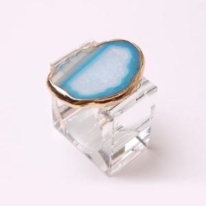 Detail of blue agate napkin ring with gold metal trim and clear acrylic square base