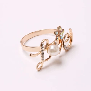 Detail of gold LOVE napkin ring featuring a large pearl and sparkling rhinestone accents