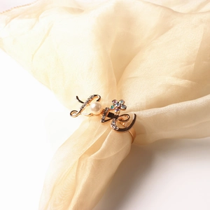 Macro shot of gold LOVE napkin ring featuring a white pearl and colorful rhinestones