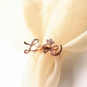 Macro detail of rose gold LOVE napkin ring with colorful rhinestones and pearl inlay