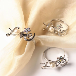 Close-up of silver Love napkin rings with pearls and rhinestone flowers on satin