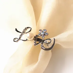 Detail of silver Love napkin ring with pearl and rhinestones on champagne silk fabric