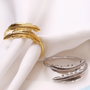 Golden and silver feather napkin rings set with detailed metallic leaf textures