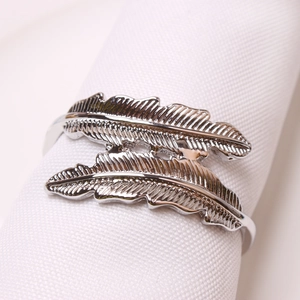 Detailed close-up of double feather silver napkin ring on a white textured napkin