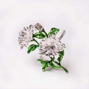 Détail du rond de serviette marguerite en argent avec feuilles en émail vert