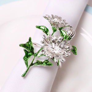 Détail d'un rond de serviette marguerite argentée avec feuilles vertes