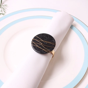 Detail of handmade napkin ring with black marble and golden wire wrap on a white napkin