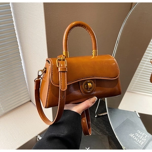 Detailed view of vintage dark brown handbag featuring golden metal turn-lock and leather handle