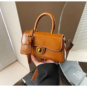 Detail view of brown leather handbag with vintage gold swivel lock and elegant handle
