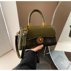 Detail of dark green glossy leather handbag with vintage gold rotary lock and round handle