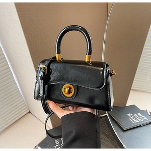 Detail of black vintage faux leather handbag showing metallic twist lock and handle