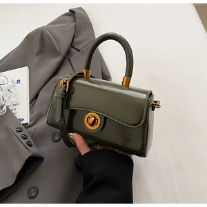 Detail of olive green structured handbag with golden circular twist lock on a blazer