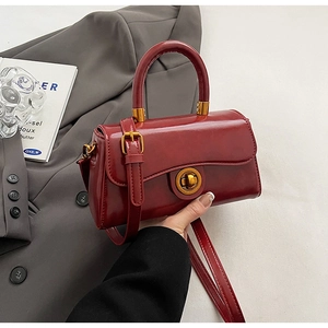 Detail of red glossy synthetic leather handbag with golden round twist lock and handle