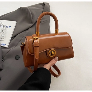 Detail of caramel faux leather shoulder bag with gold circular twist lock and handle