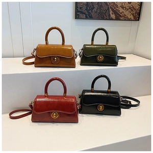 Row of retro leather handbags in brown, green, and red with gold twist locks