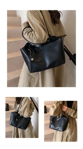 Detail of black matte tote bag with woven shoulder strap and silver bell pendant