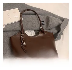 Brown leather tote bag featuring a unique wavy top edge and stylish bell charm detail