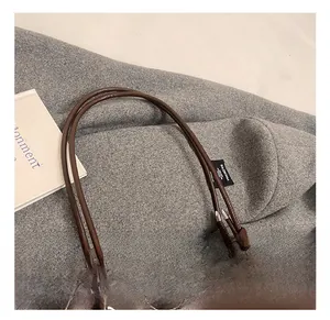 Detail of dark brown leather tote handle with knot craft and silver metal buckle