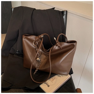 Close-up of brown leather tote bag with elegant metallic rings and knot details