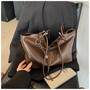 Detailed view of deep brown tote bag featuring decorative knots and woven rope accent
