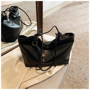 Detail of black tote bag with knot shoulder strap and black-white woven rope charm