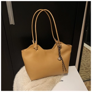Detail of light brown tote bag with wavy top edge and stylish knotted shoulder straps