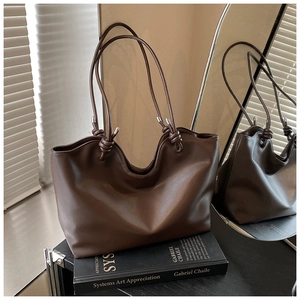 Detail of dark brown matte leather tote bag with knot strap and silver hardware accents