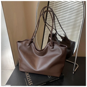 Detail of dark brown tote bag with wide knotted strap on books in a stylish home setting