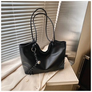 Detail of black matte leather tote bag featuring unique woven rope and metal ball charm
