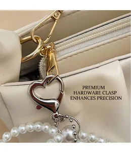 Detail of gold zipper and heart-shaped clasp with pearl bead accent on white bag