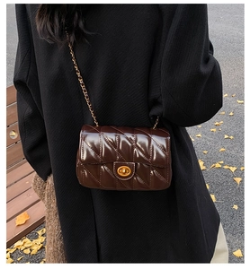 Détail du sac à bandoulière en cuir matelassé marron foncé avec chaîne dorée en automne