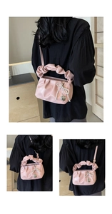 Detailed shot of pink pleated cloud bag with pearl bow and silver heart pendant detail