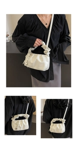 Detail of white pleated cloud bag with pearl bow charm and heart metal pendant