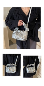 Detail of silver pleated cloud bag with pearl bow and heart pendant on shoulder strap