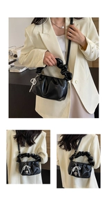 Detail of black pleated cloud bag with pearl butterfly heart charm and ruched handle